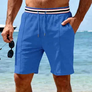Close-up of blue quick-dry running shorts featuring a striped waistband on a sunny beach.