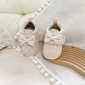 Detailed view of beige toddler girl walking shoes featuring a cute bow and heart print
