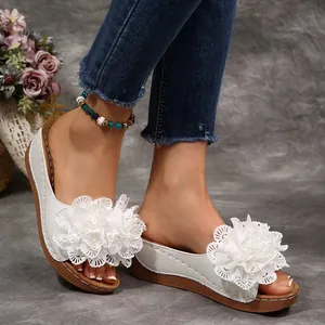 Gros plan sur des mules compensées blanches avec fleurs en dentelle portées par un mannequin