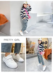 Detail view of white children's sneakers with Velcro straps for a stylish casual look.