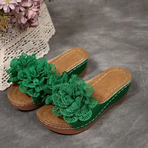 Gros plan de sandales compensées vertes avec des fleurs décoratives en dentelle.