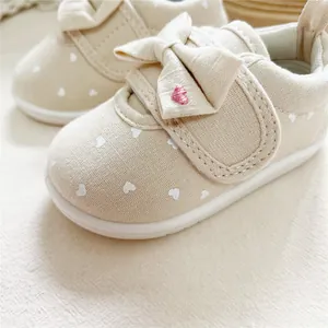 Detail view of baby girl walker shoes featuring bowknot and white heart patterns