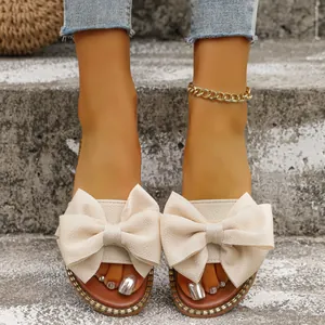 Elegantes sandalias planas de tela beige con lazo grande en los pies