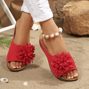 Sandales d'été rouges à talons compensés avec fleurs en tissu sur fond de plage de sable