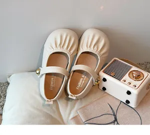 Close-up of cream Mary Jane girls' shoes with pleated details and gold bead strap