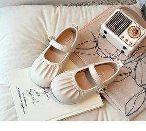 Charming beige Mary Jane shoes for girls with elegant pleats and gold button detail.