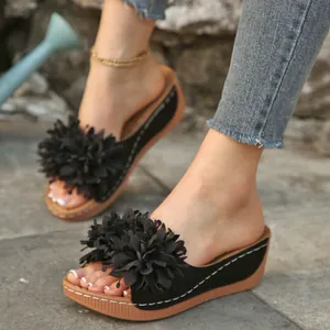 Détail de sandales compensées décontractées avec fleur noire portées en extérieur