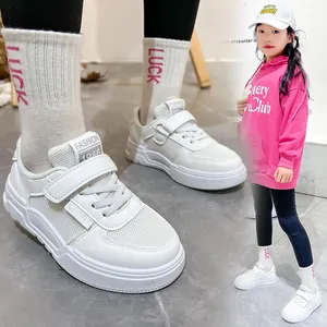 Close-up detail of white kids sneakers with velcro straps and breathable mesh upper
