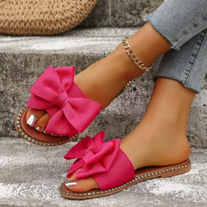 Primer plano de sandalias rosas con lazo usadas en pies con fondo de cemento gris