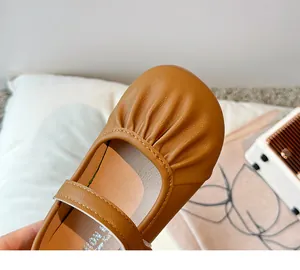 Close-up of soft brown leather girl's Mary Jane shoe with elegant pleated toe detail.