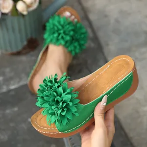 Gros plan de sandales à plateforme compensée vertes avec grande fleur en tissu