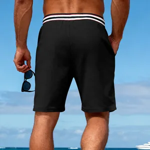 Men's black quick-dry athletic shorts with striped waistband, rear view at beach scene