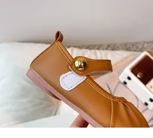 Close-up of brown toddler Mary Jane shoe with gold button and velcro strap detail