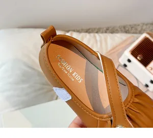 Close-up of brown girls' princess shoe with pleated leather detail and cross strap