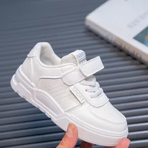 Close-up detail of white children's fashion sneaker featuring velcro strap and laces