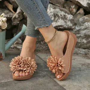 Gros plan de sandales compensées d'été avec des détails de fleurs en tissu sur le pied.