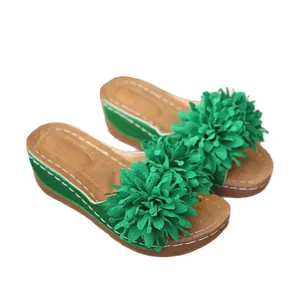 Sandales à talons compensés vertes avec décoration florale en tissu sur la bride.