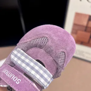 Close-up of purple girls' breathable mesh sneakers with gingham Velcro strap details.