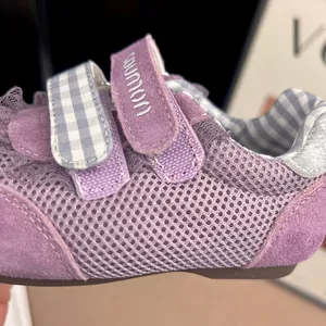 Close-up detail of purple mesh girls' sneakers with Velcro straps and plaid accents