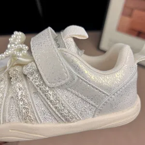 Detailaufnahme der weißen Mädchen-Glitzersneaker mit Perlenakzenten und Paillettenstreifen.