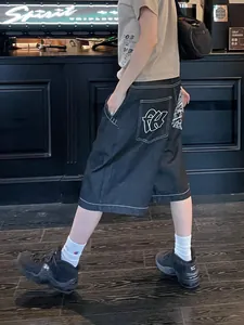 Detail der schwarzen Hip-Hop-Jeansshorts mit weißen Kontrastnähten und Stickerei.