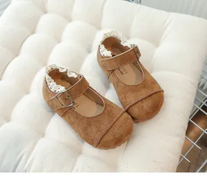 Detailed view of children's vintage brown suede shoes with lace trim and metal buckle strap