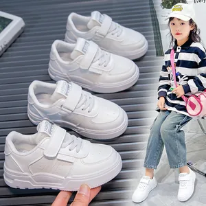 White children's sneakers with Velcro straps and soft soles shown on a young model