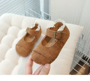 Detailed macro view of vintage brown suede children's shoes with lace trim and metal buckle.