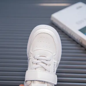 Close-up of white children's sneakers featuring a velcro strap and breathable mesh