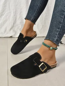 Détail des sabots noirs en daim à semelle épaisse pour femmes avec boucle sur pieds