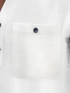 Detail view of a white textured men's Polo shirt pocket with a dark button.
