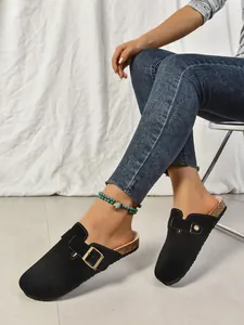 Gros plan sur des sabots plateforme en daim noir avec boucle dorée réglable pour femmes
