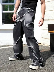 Detailed view of high-street men's denim pants with distressed patchwork and raw edges.
