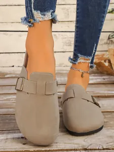 Sabots rétro en daim gris pour femmes avec bride à boucle sur sol en bois rustique