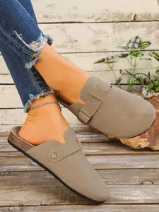 Vue rapprochée de sabots en daim taupe rétro avec une boucle et semelle en liège