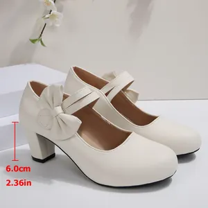 Primer plano de elegantes zapatos Mary Jane crema con tacón ancho de 6 cm y detalle de lazo