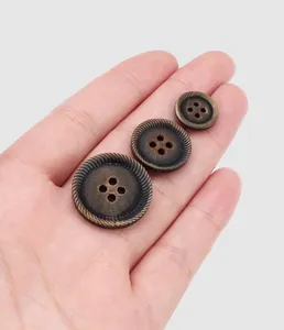 Vista detallada de tres botones de cuerno marrón vintage en varios tamaños en mano