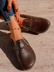 Gros plan de sabots rétro tressés marron avec boucle réglable portés par un mannequin pro.