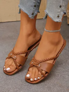 Detailansicht der braunen geflochtenen flachen Damen-Sandalen mit schicken Metallnieten