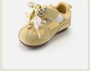 Detailed view of yellow toddler retro sneakers featuring a floral bow lace and soft sole