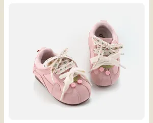 Detailed view of pink baby walking shoes with cherry accents and ribbon laces