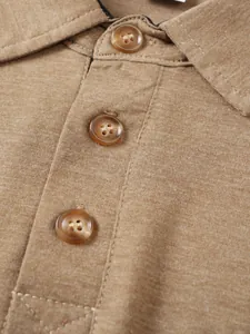 Primer plano de la tapeta de botones y el cuello de un polo caqui de manga corta.