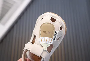 Detailaufnahme einer beigen Babysandale mit einem niedlichen Cartoon-Milchflaschen-Design