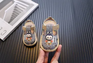 Primer plano de sandalias grises para bebé con mascota de conejo de dibujos animados.
