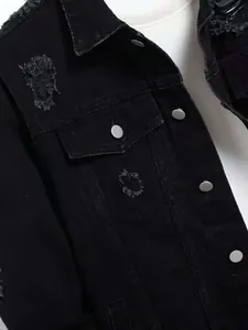 Close-up of black distressed denim jacket with metal buttons and chest pocket detail.