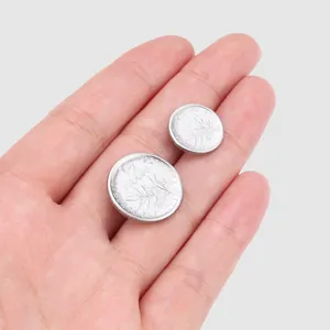 Set of silver metal decorative buttons with vintage French coin engraving held in hand
