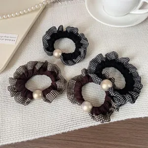 Macro view of ruffled checkered hair scrunchies with elegant beige pearl ornament