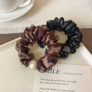 Detail view of elegant leopard print and black mesh scrunchies with large pearl bead