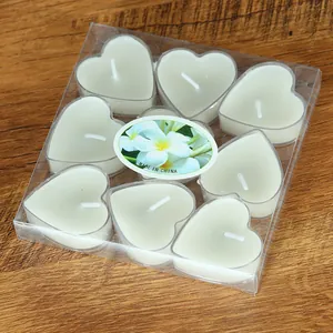 Set aus 9 romantischen weißen herzförmigen Teelichtern in einer klaren PVC-Geschenkbox auf Holz