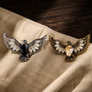 Close-up detail of retro eagle brooches with crystals and cat eye wings on fabric